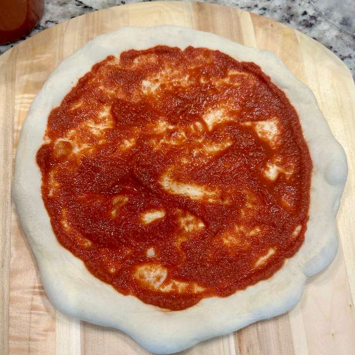 Stretched dough with pizza sauce